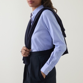 Model wearing Hugo Boss light pastel purple cotton blouse, styled with a navy blazer draped over shoulders and dark tailored trousers.
