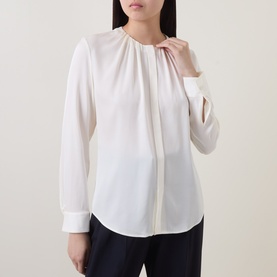 Model wearing Hugo Boss Optic White silk blouse with gathered neckline, long sleeves and button placket, styled with navy trousers.