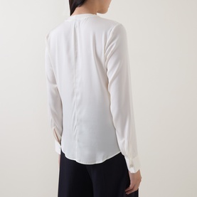 Model wearing Hugo Boss optic white silk blend blouse, rear view showing relaxed fit and long sleeves, styled with dark trousers.