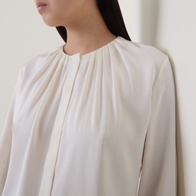 Model wearing Hugo Boss Optic White silk blouse with gathered neckline and long sleeves, close-up detail shot
