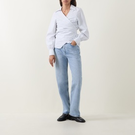 Model wearing Hugo Boss light purple cotton blouse with wrap front and puff sleeves, styled with pale blue straight-leg jeans and black loafers