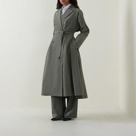 Model wearing sage green belted longline trench coat with wide-leg trousers and black shoes