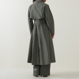 Model wearing a khaki green belted trench coat, shown from behind, with wide-leg trousers in matching tone.