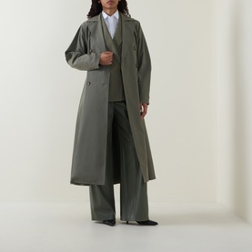 Model wearing an olive green longline belted trench coat, styled with matching wide-leg trousers, a white shirt, and black shoes.