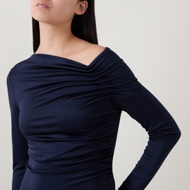 Model wearing Hugo Boss dark blue ruched long-sleeve dress with asymmetric off-shoulder neckline, close-up detail view.