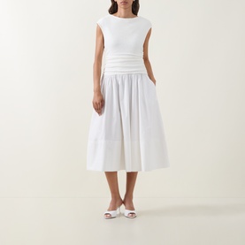 Model wearing Hugo Boss white midi dress with ribbed bodice, gathered waist and full cotton skirt, styled with white mule heels