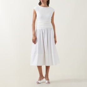 Model wearing Hugo Boss white midi dress with ribbed fitted bodice, gathered waist and full cotton skirt, styled with white heeled mules.