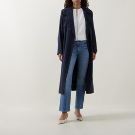 Model wearing Hugo Boss medium blue straight-leg jeans, styled with a navy longline coat and white top, beige heels.