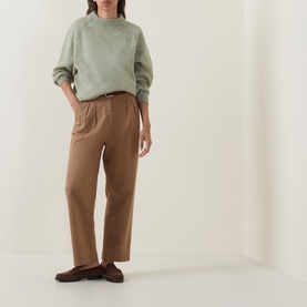 Model wearing Hugo Boss Fewena Brushed Sweater in Open Green with mock neck and ribbed trims, styled with camel wide-leg trousers and dark loafers.