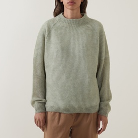 Model wearing Hugo Boss Fewena Brushed Sweater in Open Green, mock neck, ribbed knit, styled with tan trousers