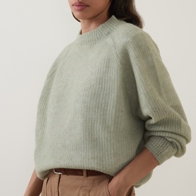Model wearing Hugo Boss Fewena Brushed Sweater in Open Green, ribbed mock neck, rounded shoulders, styled with tan trousers and belt.