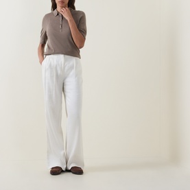 Model wearing Hugo Boss Fidenka Knitted Polo Shirt in Brown Overflow, styled with wide-leg white trousers and brown loafers.