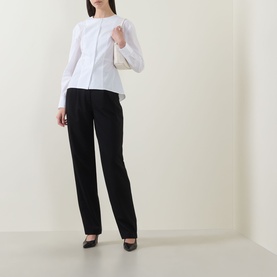 Model wearing Hugo Boss Beplum Collarless White Shirt with dropped shoulders and flared hem, styled with black straight-leg trousers and heels.