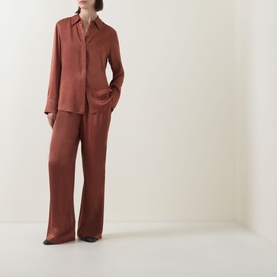 Model wearing Hugo Boss rust copper viscose shirt with matching wide-leg trousers and black shoes.