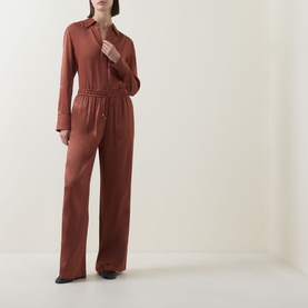Model wearing Hugo Boss rust/copper wide-leg jumpsuit with shirt collar, long sleeves and drawstring waist in 100% viscose