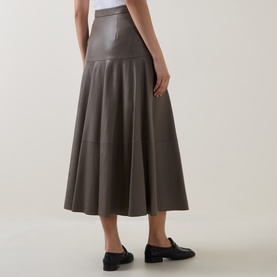 Model wearing Hugo Boss Brown Overflow leather midi skirt with flared panelled silhouette, styled with black loafers. Rear view.