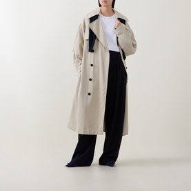 Model wearing Hugo Boss white top, styled with a beige colour-block trench coat and wide-leg black trousers.