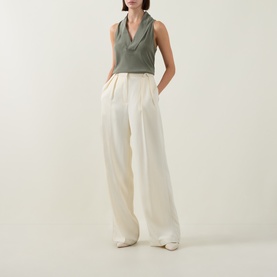 Model wearing Hugo Boss Bolaru Silk Blouse in dark green with shawl collar, styled with cream wide-leg trousers and white flat shoes.