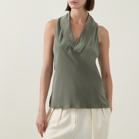 Model wearing Hugo Boss Bolaru Silk Blouse in dark green with shawl collar V-neckline and sleeveless cut, styled with cream wide-leg trousers