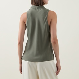 Model wearing Hugo Boss Bolaru Silk Blouse in dark green, showing sleeveless back view with shawl collar and straight hem, styled with cream wide-leg