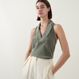 Model wearing Hugo Boss Bolaru Silk Blouse in dark green with shawl collar V-neckline, styled with cream wide-leg trousers