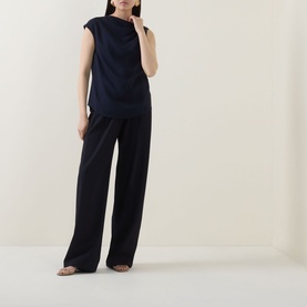 Model wearing Hugo Boss Bannea Draped Top in dark blue with asymmetrical neckline, styled with matching wide-leg trousers.