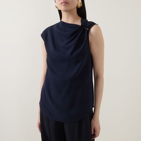 Model wearing Hugo Boss Bannea Draped Top in dark blue, sleeveless with asymmetric neckline and gold-tone pin hardware, styled with wide-leg trousers