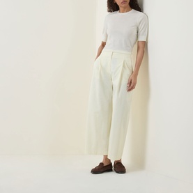 Model wearing Hugo Boss Farbella Knit Top in Open Beige with crew neck, styled with cream wide-leg trousers and brown loafers