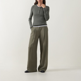 Model wearing Hugo Boss dark green wool long-sleeve henley top with contrast trim, styled with wide-leg khaki trousers and black loafers.