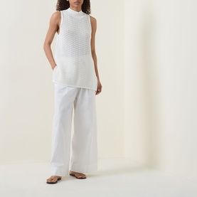 Model wearing Hugo Boss Open White sleeveless cotton mesh top with wide-leg white trousers and brown flat sandals.