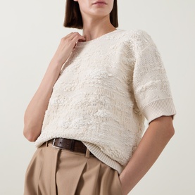 Model wearing Hugo Boss Open White textured short-sleeve knit top, styled with beige tailored trousers and brown belt.