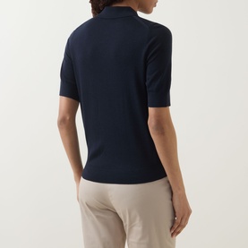 Model wearing Hugo Boss dark blue virgin wool polo top, short sleeves, ribbed collar, back view, styled with stone trousers