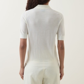 Model wearing Hugo Boss open beige virgin wool knit polo top, short sleeves, ribbed collar and hem, styled with matching trousers. Back view.