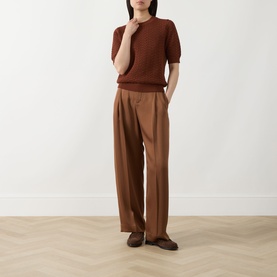 Model wearing Hugo Boss rust/copper cotton knit short-sleeve top with wide-leg camel trousers and brown loafers.