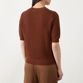 Model wearing Hugo Boss rust/copper cotton knit top, back view, textured crochet-style pattern, short sleeves, styled with wide-leg trousers.