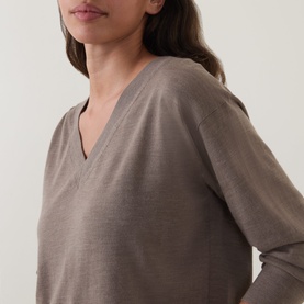 Model wearing Hugo Boss Brown Overflow 100% virgin wool V-neck long-sleeve top, close-up detail of neckline and sleeve.