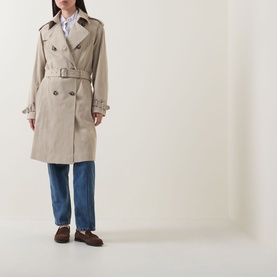 Model wearing Hugo Boss Caomy Double-Breasted Trench Coat in Beige Overflow with blue wide-leg jeans and brown loafers.