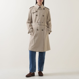 Model wearing Hugo Boss Caomy Double-Breasted Trench Coat in Beige Overflow with belted waist, styled with blue jeans and brown loafers