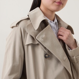 Model wearing Hugo Boss Caomy Double-Breasted Trench Coat in Beige Overflow, showing collared neckline with throat latch and button fastening detail