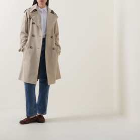 Model wearing Hugo Boss Caomy Double-Breasted Trench Coat in Beige Overflow, styled with blue wide-leg jeans and brown loafers