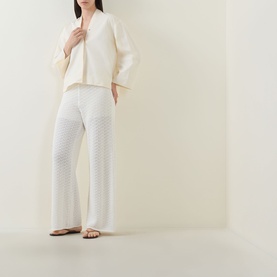Model wearing Hugo Boss Fangrove Knitted Wide-Leg Trousers in Open White with matching white knit jacket and brown sandals.