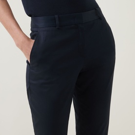 Model wearing navy tailored trousers with belt loops and side pocket, styled with a navy top