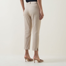 Model wearing Hugo Boss Beige Overflow slim-fit trousers, cropped length with side slit hem, paired with gold heeled mules.
