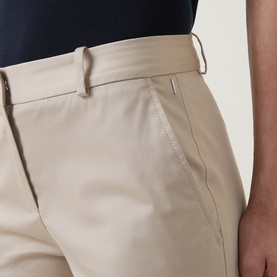 Model wearing Hugo Boss beige trousers, close-up of waistband and front pocket detail in cotton-blend fabric