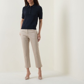 Model wearing Hugo Boss Beige Overflow cropped trousers with navy short-sleeve polo shirt and nude heels.