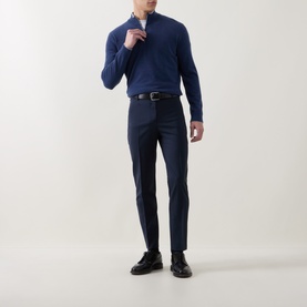 Model wearing Hugo Boss Tapriah Dark Blue slim leg mid-rise trousers with a navy zip-neck knit and black leather shoes.