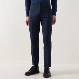 Model wearing Hugo Boss Tapriah Dark Blue slim leg mid-rise trousers with pressed creases, styled with a navy jumper and black loafers
