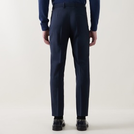 Model wearing Hugo Boss Tapriah Mid-Rise Slim Leg Trousers in dark blue wool, rear view, styled with navy jumper and black shoes.