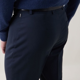 Model wearing Hugo Boss Tapriah Mid-Rise Slim Leg Trousers in dark blue wool, styled with a navy knit and black leather belt.