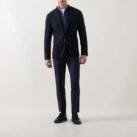 Model wearing Hugo Boss Tapriah Dark Blue slim leg mid-rise trousers, styled with a navy blazer, blue knit and black loafers.